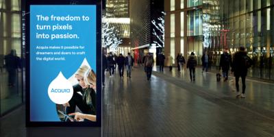 Color photograph of urban street scene at night with a digital ad display in the foreground