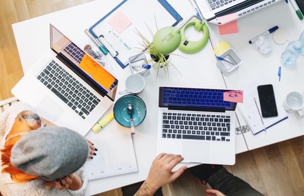 Aerial view of desk with two people working on laptops