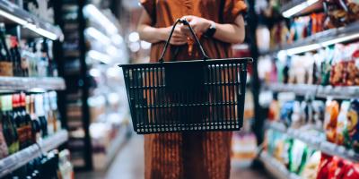 Color photo of woman shopper with grocery basket standing in a store aisle