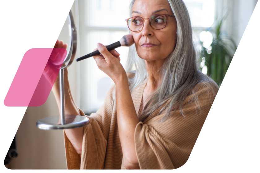 image of a woman applying makeup cropped by the shape of a parallelogram and another pink parallelogram overlapping