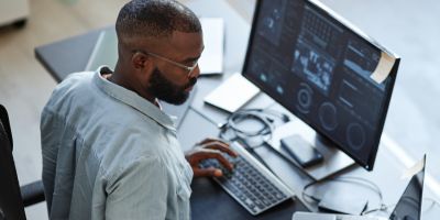 Overhead shot of Black male sitting at desk and looking at a computer monitor