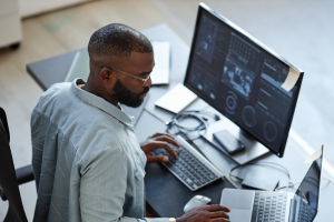 Overhead shot of Black male sitting at desk and looking at a computer monitor