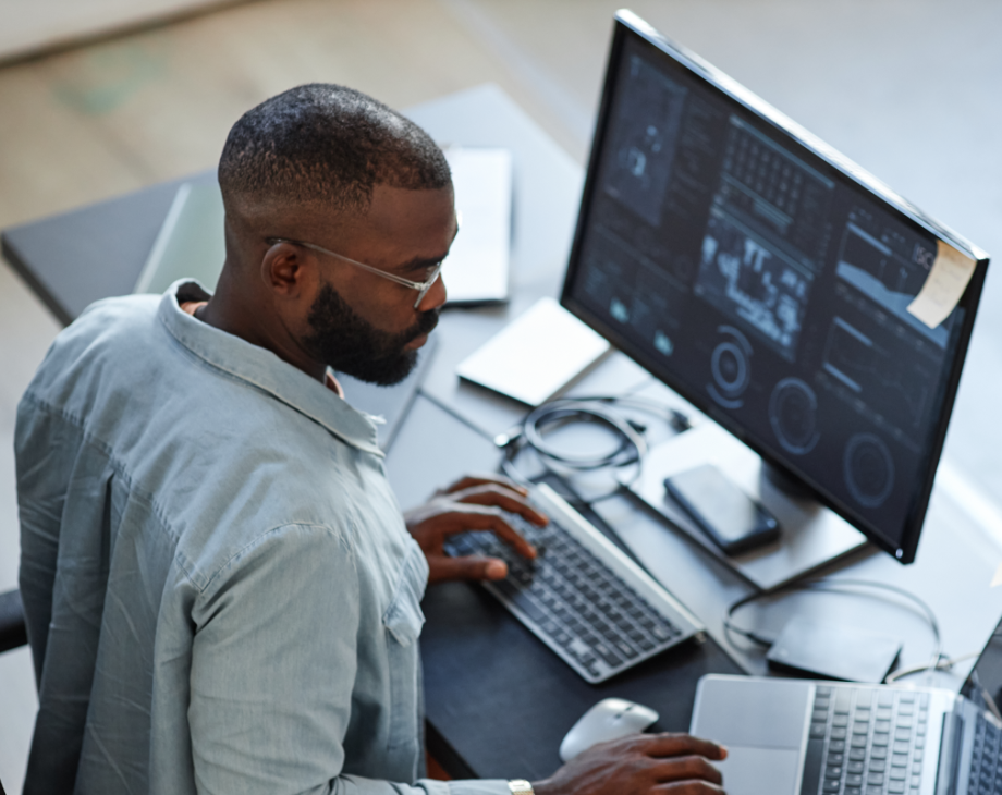 Overhead shot of Black male sitting at desk and looking at a computer monitor