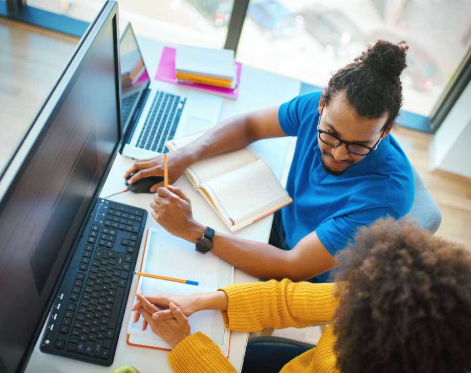 Overhead color shot of two coworkers in discussion in front of a computer monitor