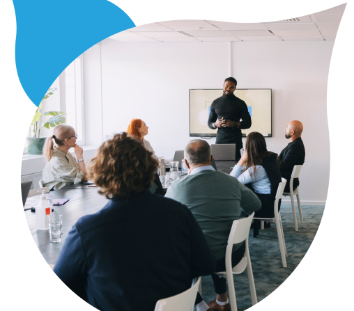 people around a conference table listening to someone speak masked in an acquia droplet logo